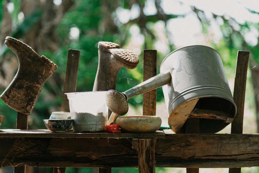 Équipements de jardinage anciens avec arrosoirs et outils sur table en bois, équipements de jardinage variés