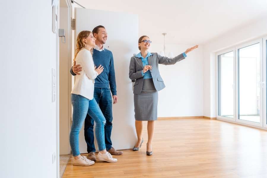 Une agente immobilière présente un appartement vide à un jeune couple durant la recherche de votre locataire.