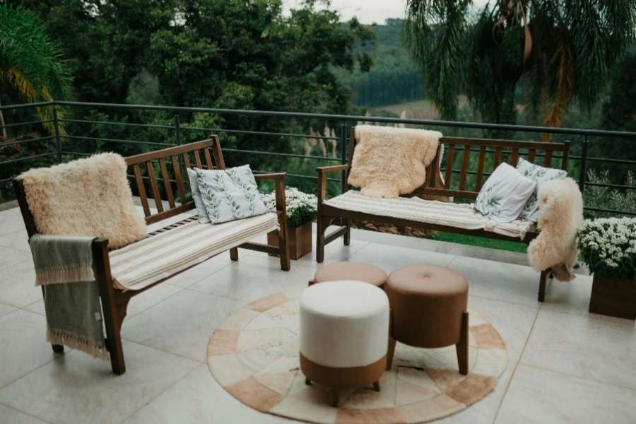 Un salon de jardin chaleureux installé sur un carrelage de terrasse terne avec vue sur la nature.