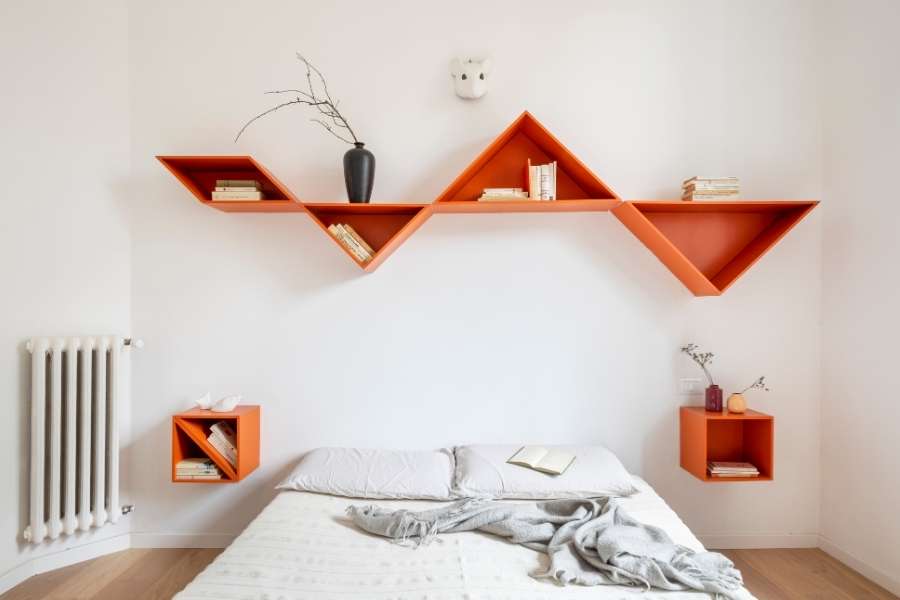Une chambre lumineuse décorée avec des étagères murales géométriques orange au-dessus du lit