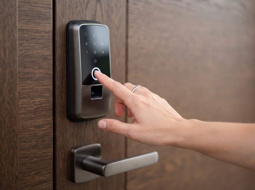 Une main utilise le clavier numérique d'une serrure intelligente sur une porte en bois pour installer serrure connectée intelligente serrurier paris.